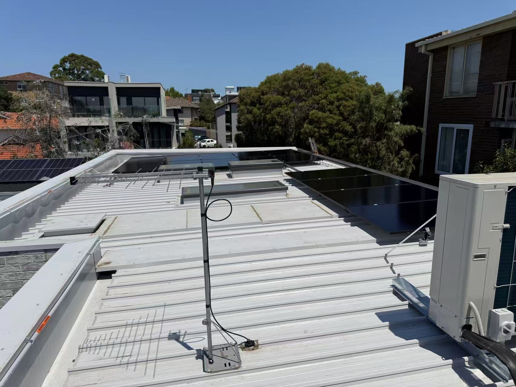 Mixed tilt and flush solar array layout around rooftop services in Kew